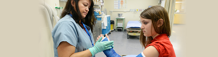 A health-care team member applies a wrist cast to an adolescent patient in the Fracture Clinic.