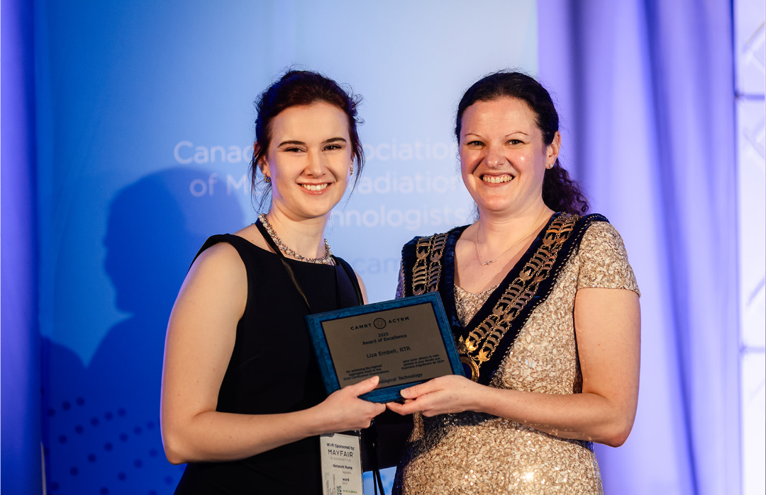 Two women holding an award plaque on stage