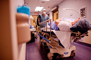 Healthcare worker pushing patient on hospital bed
