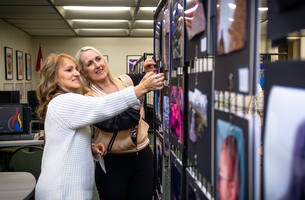 Two women looking at art on a wall