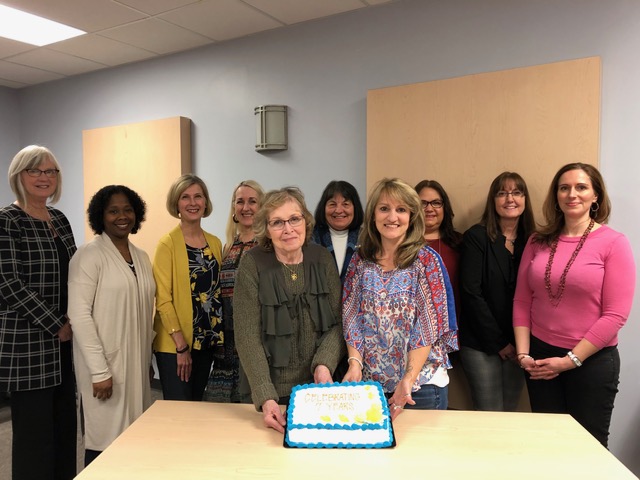 Group photo with two people holding a cake