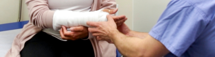 A doctor performs an exam on a patient with a cast on their arm