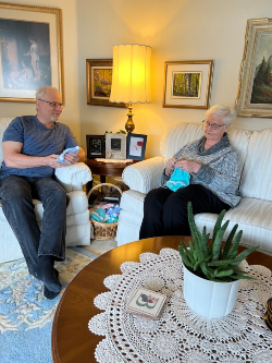 Marilyn (L) knits a cap while her son Mike (R) looks on