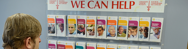 man standing in front of a wall of brochures