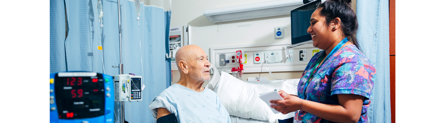 Nurse speaking to patient in hospital room.